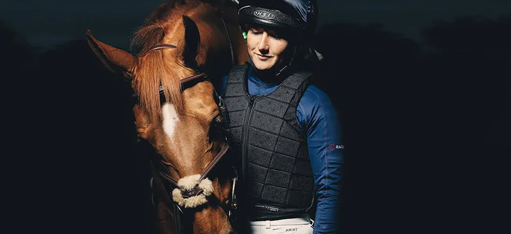Woman wearing Racesafe ProVent 3.0 body protector standing next to chestnut horse.